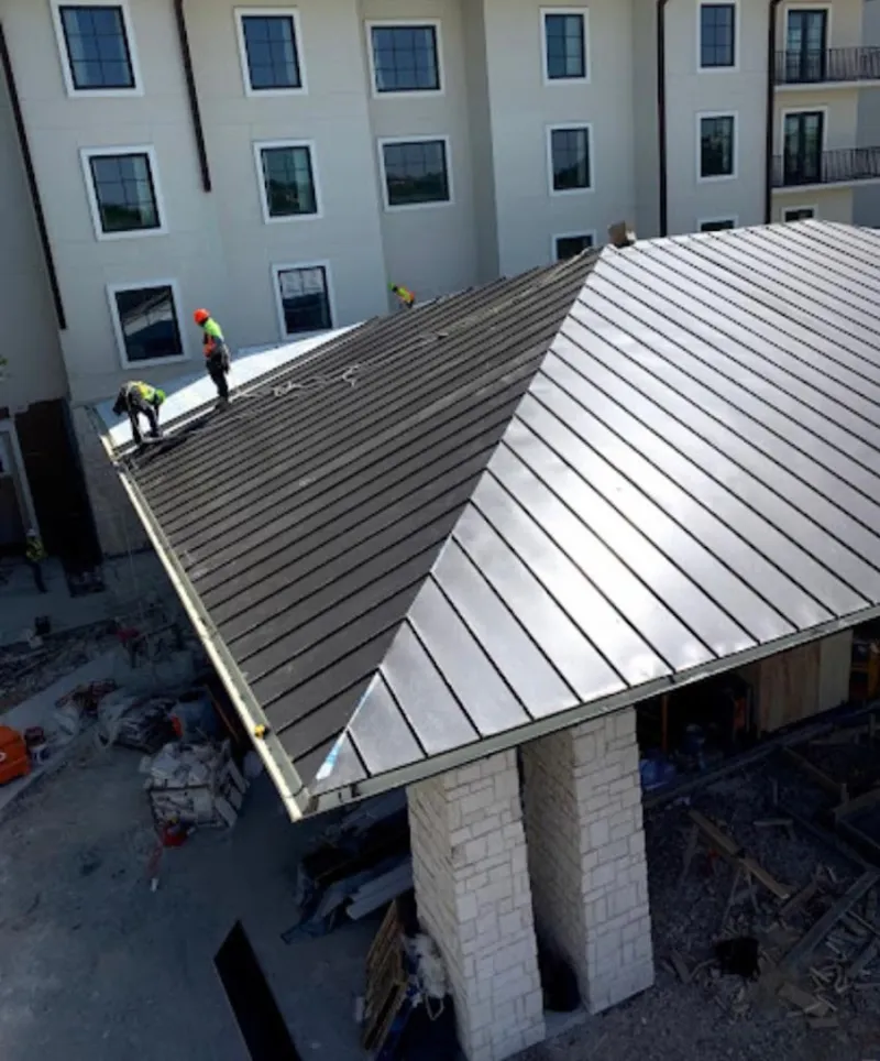 Crew installing standing seam metal roof panels on a commercial project in Badger